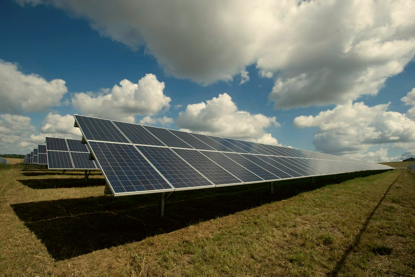 Rows of solar panels in a field under a cloudy sky