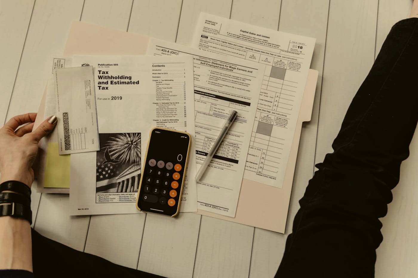Printed tax and financial forms on a desk with a calculator and a pen